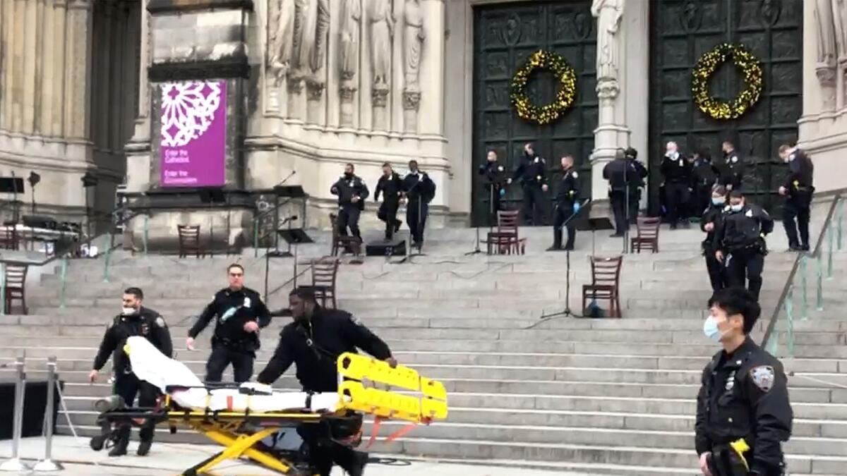 Emergency medical personnel pull a stretcher up to the scene of a shooting at the Cathedral Church of St. John the Divine. AP