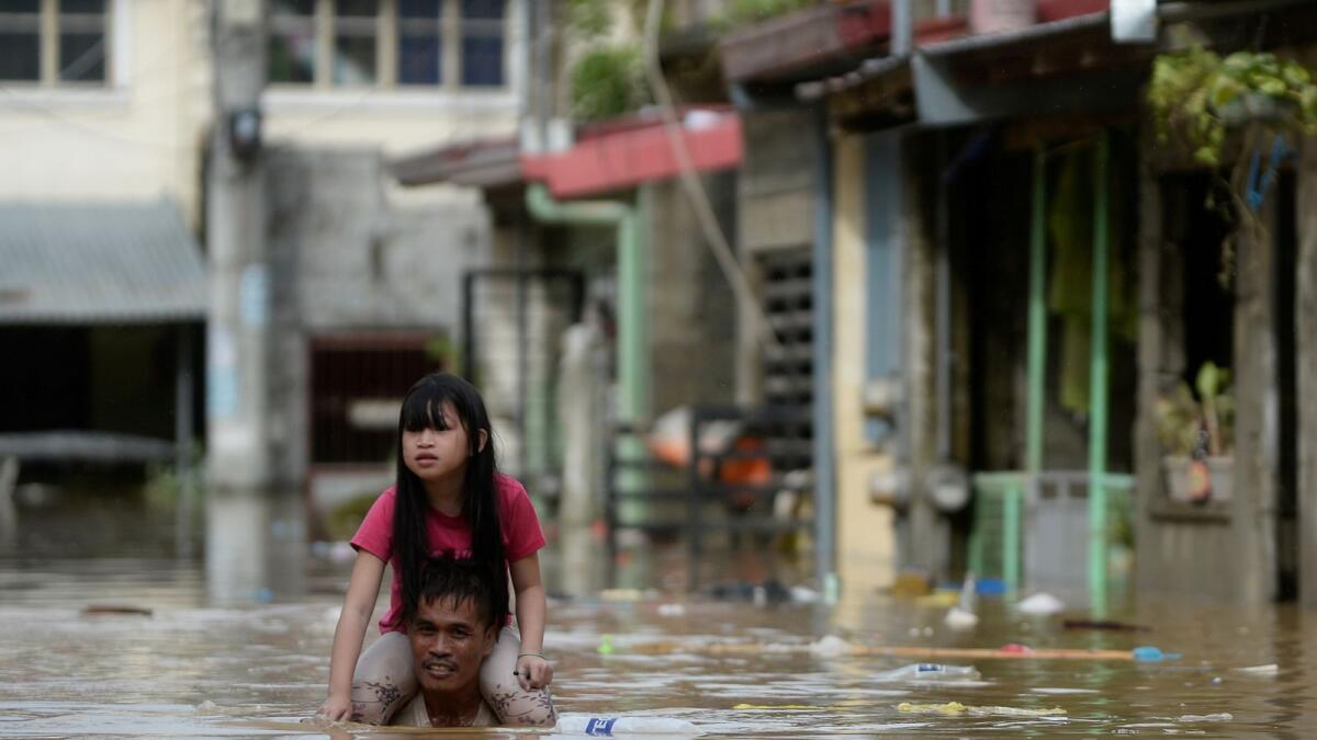 A man carrying a child on his shoulders wades through a flooded street following Typhoon Vamco, in Rizal Province, Philippines, November 12, 2020.