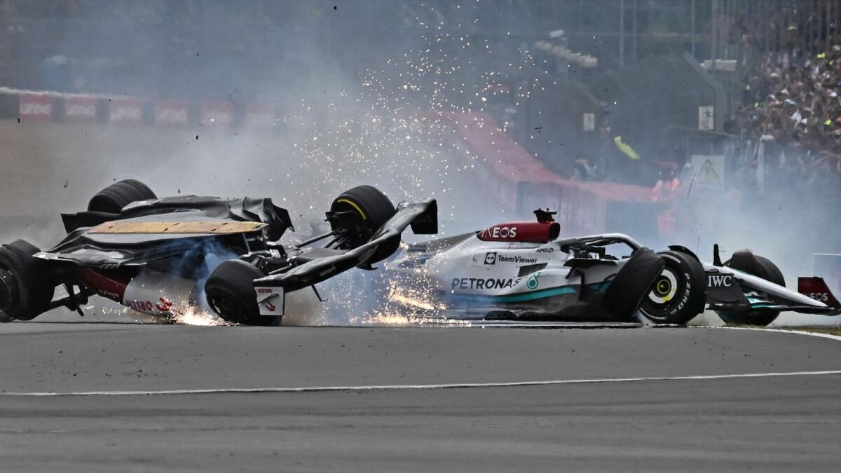 Alfa Romeo's Chinese driver Zhou Guanyu (left) and Mercedes' British driver George Russell (right) skid across the track after a collision at the start of the British Grand Prix  on Sunday. (AFP)