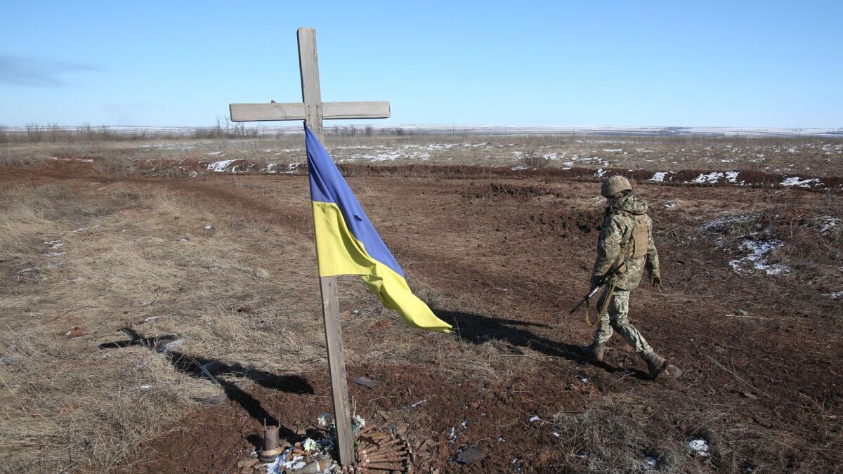 A Ukrainian soldier walks past a self made memorial to late soldier-mates in Svetlodarsk outside Donetsk, on March 12, 2022. (Photo by Anatolii Stepanov / AFP)