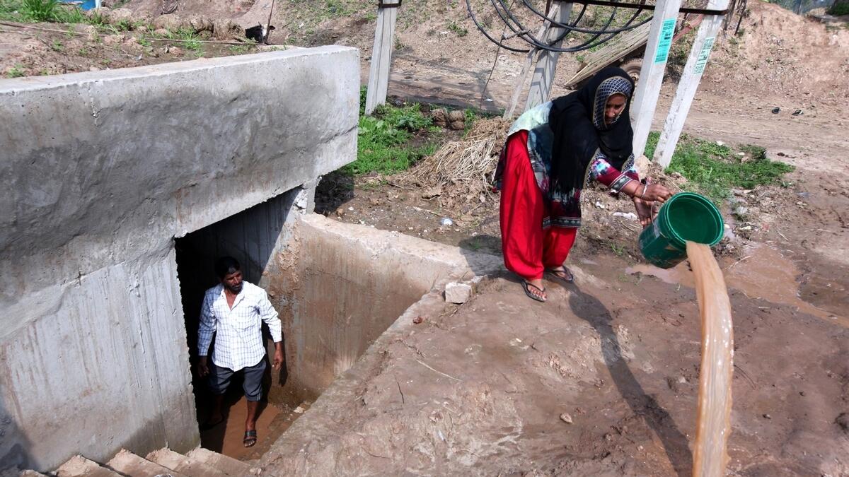 Indian villagers living along the India-Pakistan border remove water from a bunker near Jammu.-AFP 