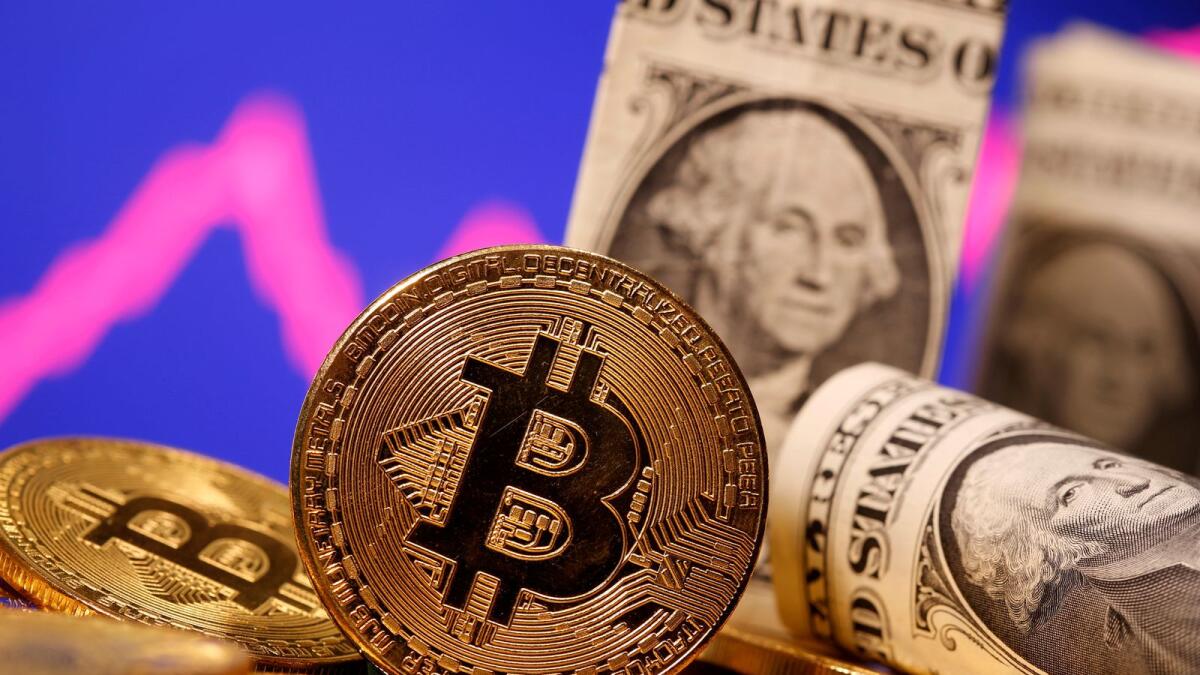 A representation of virtual currency Bitcoin and US one dollar banknotes are seen in front of a stock graph in this illustration. — Reuters file 
