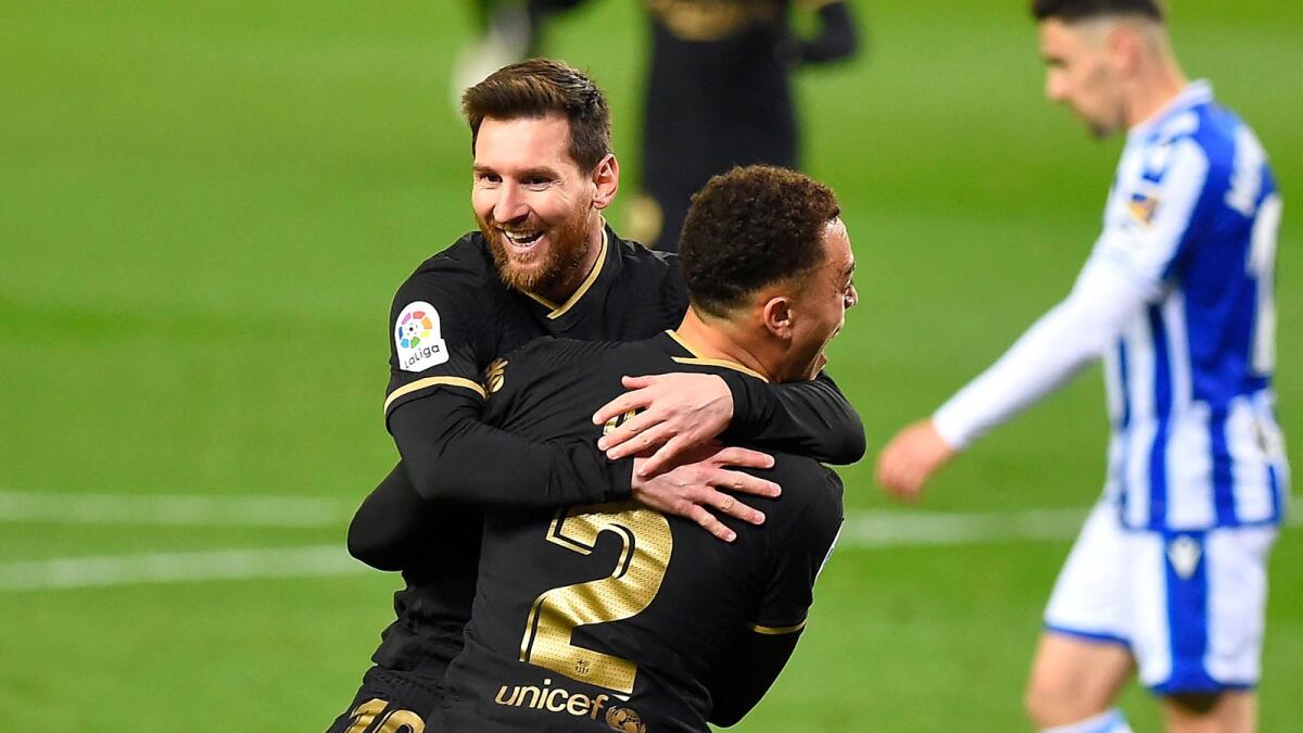 Barcelona's Sergino Dest celebrates with Lionel Messi after scoring a goal against Real Sociedad. — AFP
