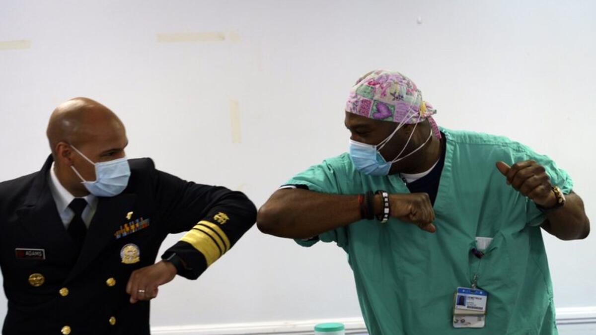 Surgeon General of the U.S. Jerome Adams, left, elbow-bumps Emergency Room technician Demetrius Mcalister after Mcalister got the Pfizer COVID-19 vaccination at Saint Anthony Hospital in Chicago, on Tuesday, Dec. 22, 2020