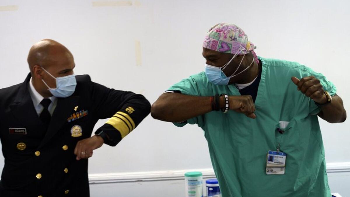 Surgeon General of the U.S. Jerome Adams, left, elbow-bumps Emergency Room technician Demetrius Mcalister after Mcalister got the Pfizer COVID-19 vaccination at Saint Anthony Hospital in Chicago, on Tuesday, Dec. 22, 2020