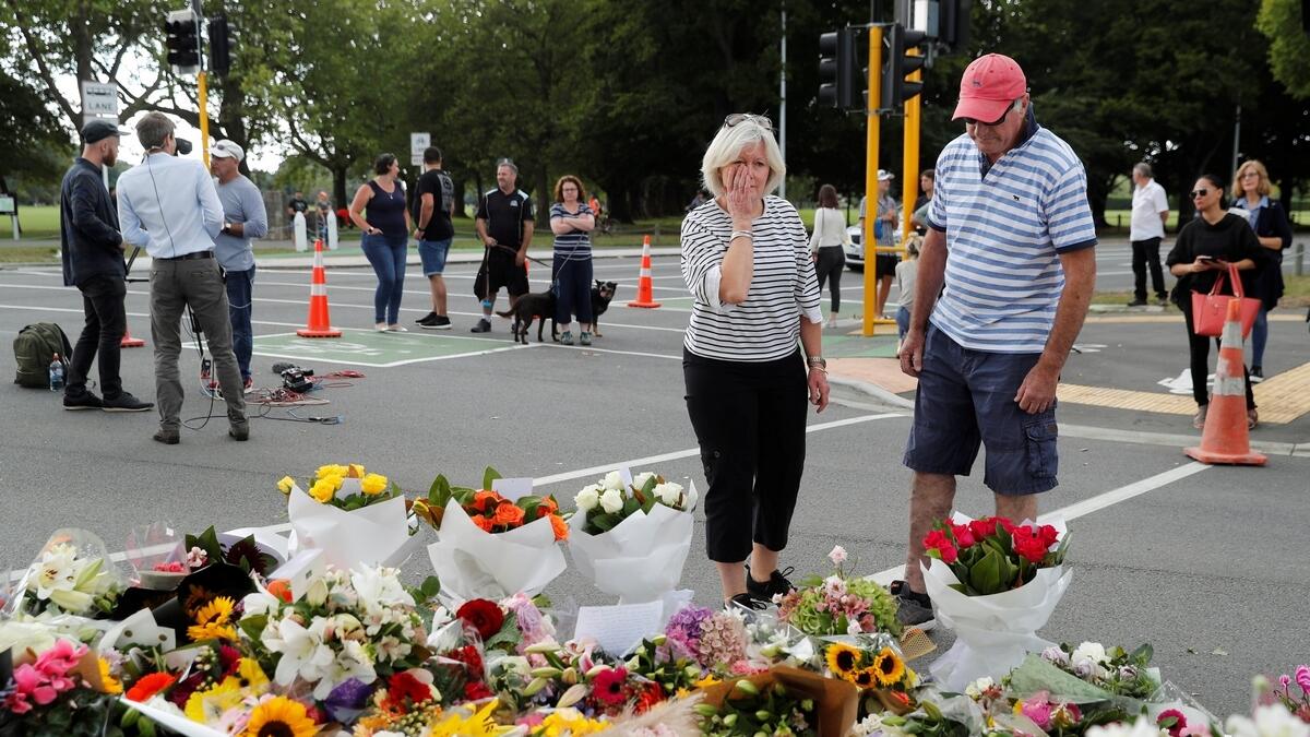 People react near flowers placed at a memorial as a tribute to victims of the mosque attacks, near a police line outside Masjid Al Noor in Christchurch, New Zealand.- Reuters