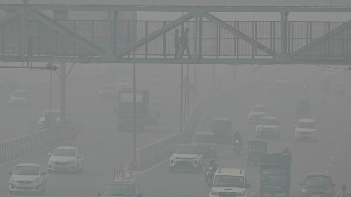 Commuters make their way along a road amid heavy smoggy conditions in New Delhi on November 5, 2023. — AFP