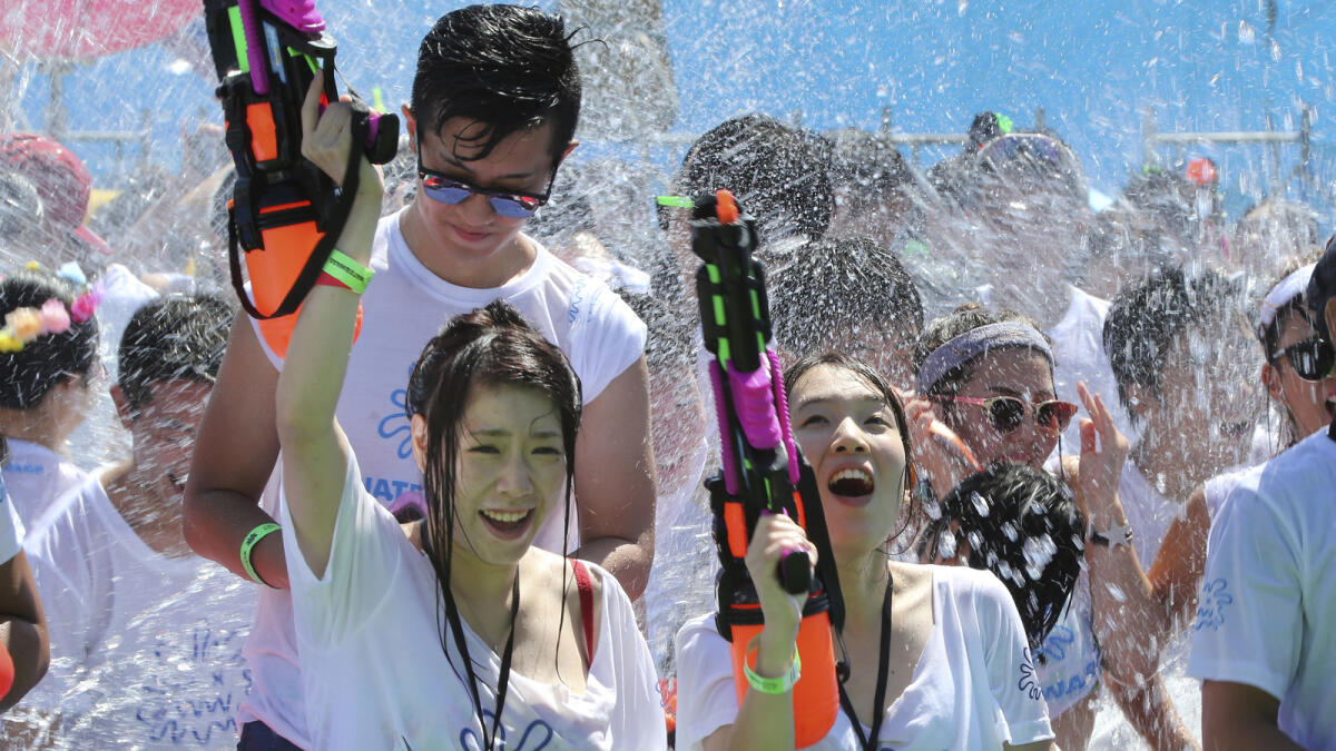 Participants with water guns dance along music as they are splashed water during the first 'Waterwars' in Tokyo, Saturday, Sept. 3, 2016. Several hundreds of people gathered for the summer event inspired by the famous water festival in Thailand as the temperature soared to 31 degrees Celsius (87.8 degrees Fahrenheit) in the Japanese capital. (AP Photo/Koji Sasahara)