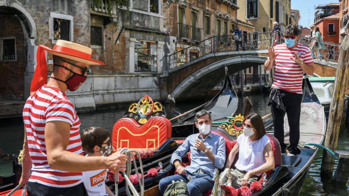 Gondoliers go with customers for a gondola ride on a canal in Venice on June 12, 2020 as the country eases its lockdown aimed at curbing the spread of the COVID-19 infection, caused by the novel coronavirus. Photo: AFP