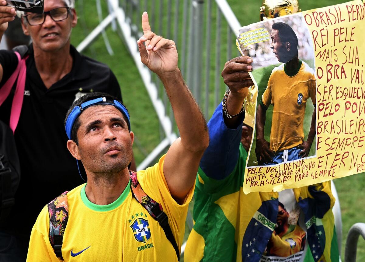 A fan of late Brazilian football legend Pele gestures while attending his wake at the Urbano Caldeira stadium in Santos, Sao Paulo, Brazil on Tuesday. — AFP