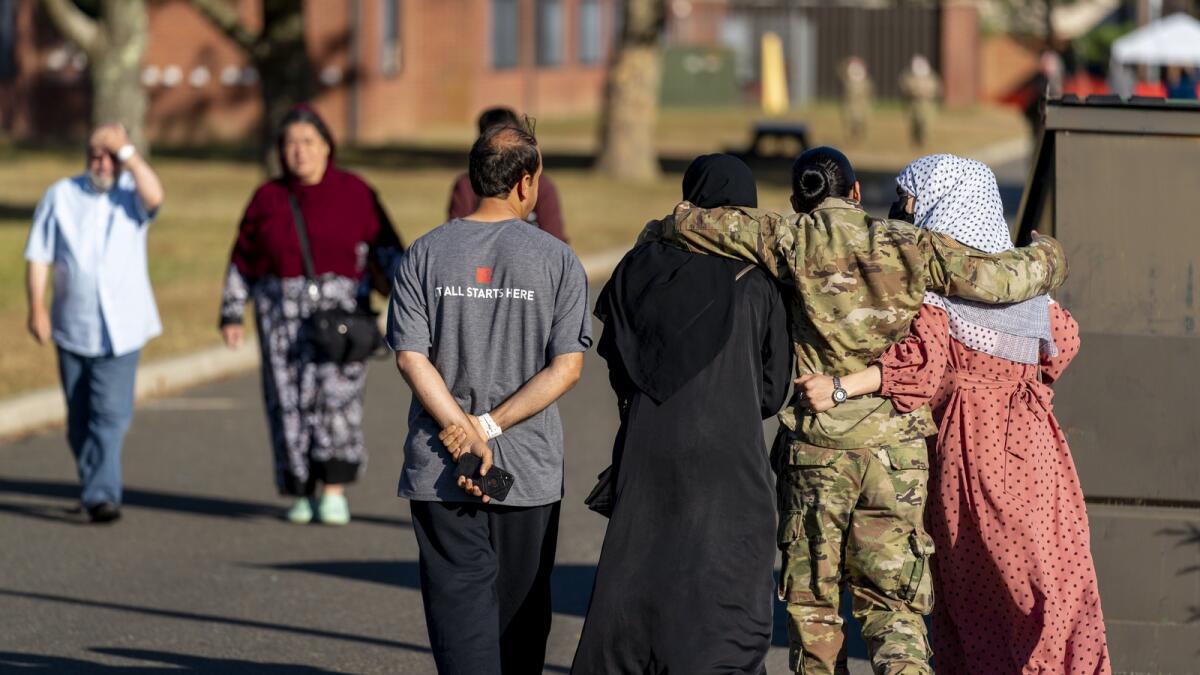 A female member of the military puts her arms around two female Afghan refugees after they spoke with Secretary of Defense Lloyd Austin as he visits an Afghan refugee camp on Joint Base McGuire Dix Lakehurst, N.J., Sept. 27, 2021. — AP file