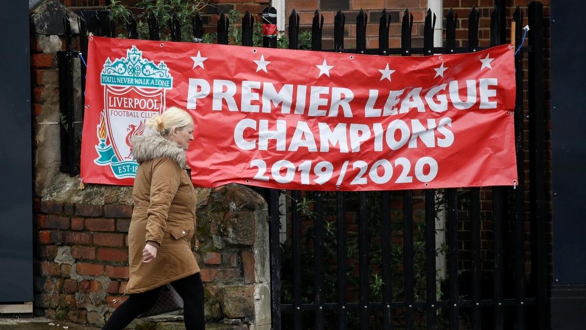 A woman walks past a banner stating 'Premier League Champions 2019/2020' in Liverpool.