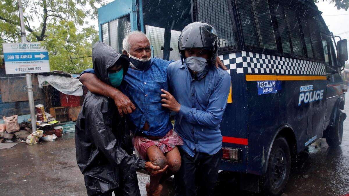 Police officers carry a disabled man to a safer place following his evacuation from a slum area before Cyclone Amphan makes its landfall, in Kolkata, India, May 20, 2020.