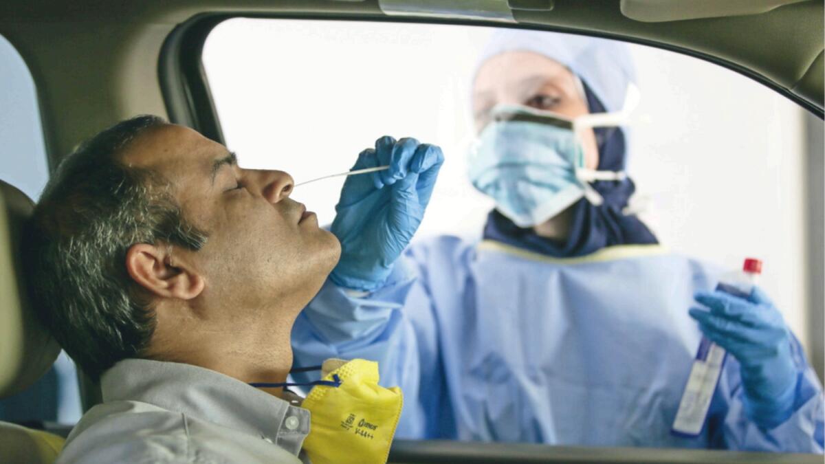 A health worker collects nasal swab for PCR test at a drive-through testing centre in Abu Dhabi. — File photo by Ryan Lim