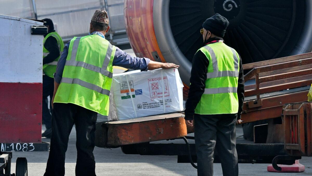 Airport workers unloading a box containing Covishield.