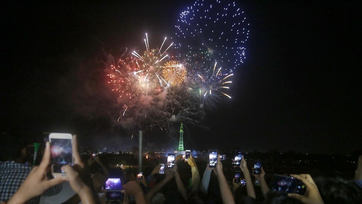 People use their mobile phones to film fireworks close to the Minar-e-Pakistan or Pakistan monument during the Pakistan Independence Day celebrations, in Lahore, Pakistan. Photo: AP