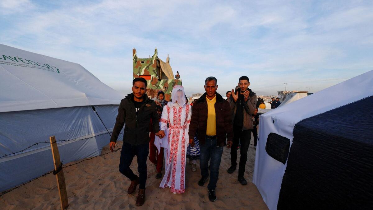 Mohammed Al Ghandour and Shahad walk on their wedding day in the tent camp in Rafah in the southern Gaza Strip. — Reuters