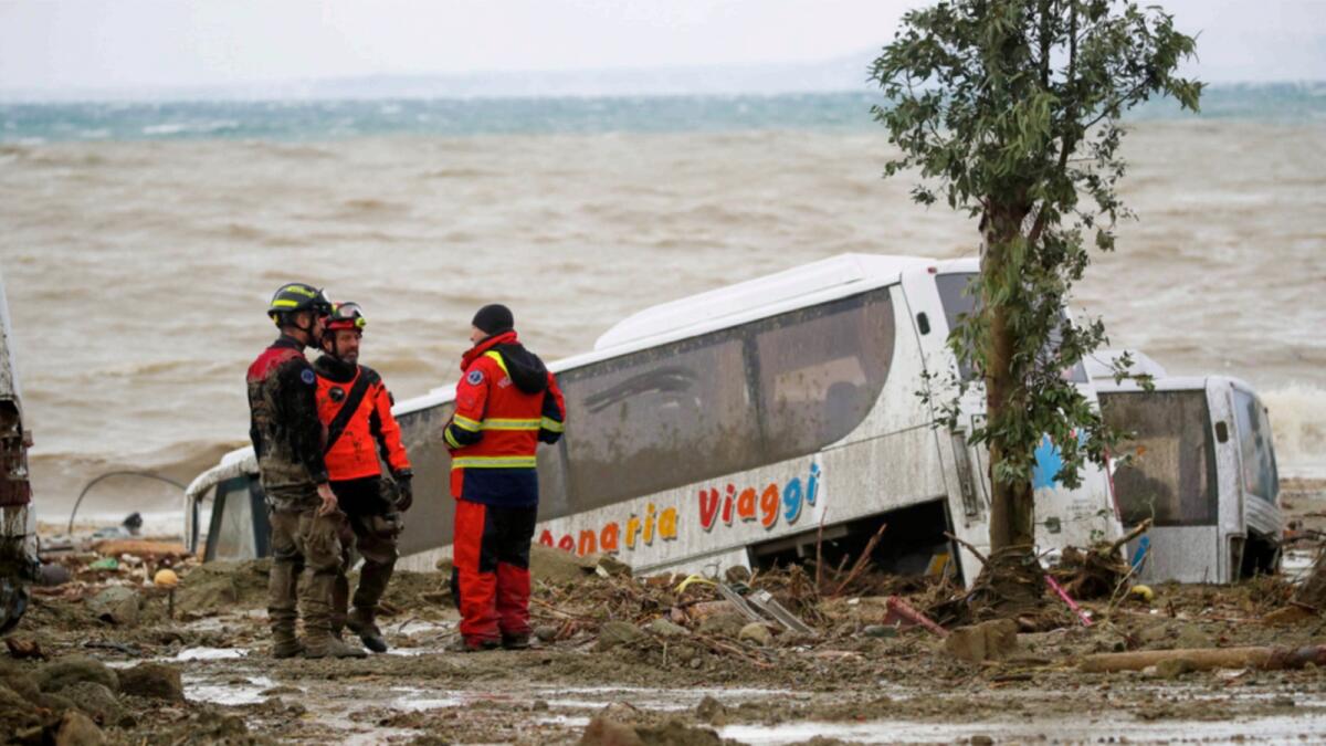 Rescuers stand next to a bus carried away after heavy rainfall triggered landslides that collapsed buildings and left as many as 12 people missing, in Casamicciola, on the southern Italian island of Ischia. — AP