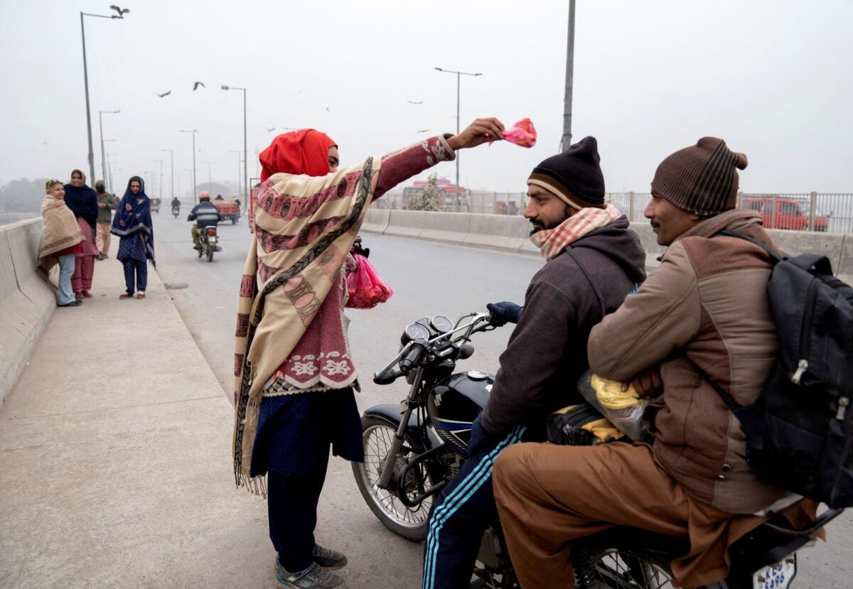 A woman blesses a customer with meat to feed the birds in Lahore. — Reuters