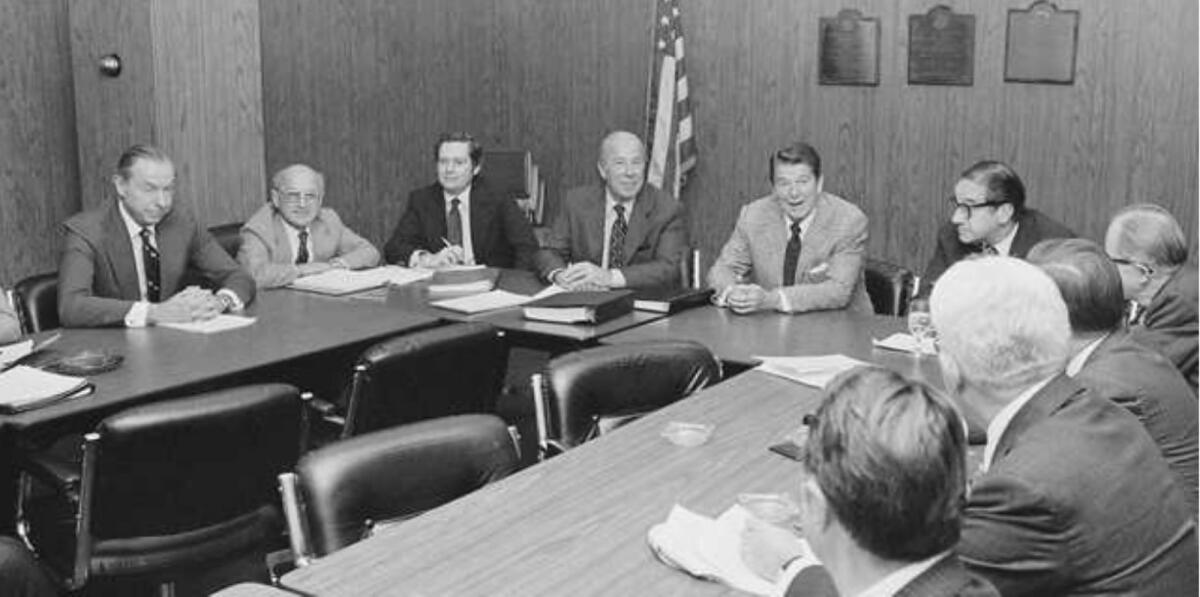 Then president-elect Ronald Reagan meets  his top economic advisers at the Los Angeles Federal Building. Advisers that are identifiable in the picture are left to right: Walter Wriston, Milton Friedman, Daryl Trent, George Shultz, Ronald Reagan, Paul McCracken. The group put the finishing touches on a new economic policy which they presented to Reagan amid indications it strays little for the President-elect's campaign promises.