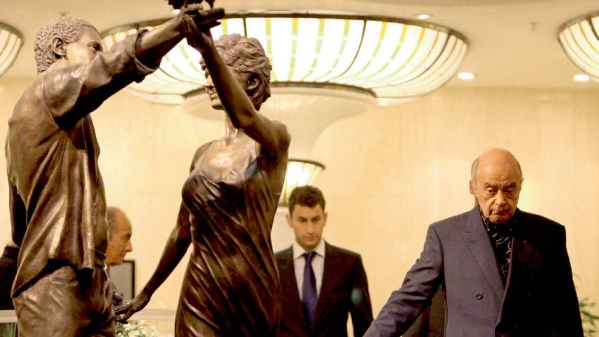 Mohamed Al Fayed (R) walks past a statue of his son Dodi and Diana, Princess of Wales, after observing a two-minute silence in memory of them at Harrods Department Store in London — AFP file