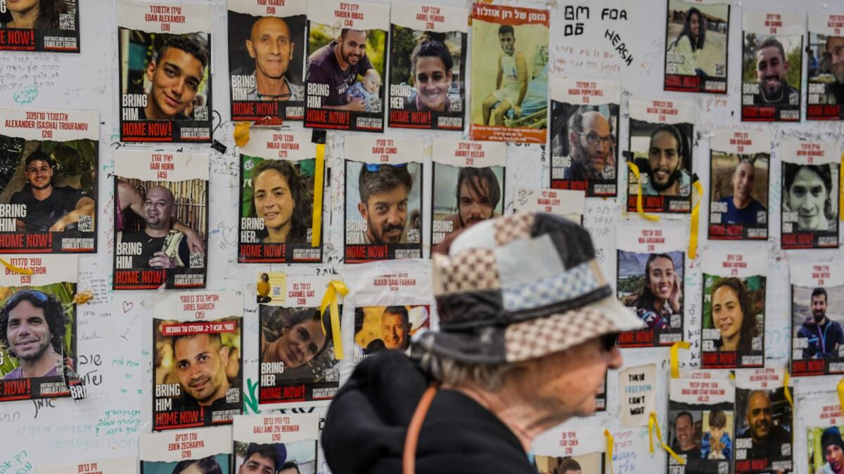 A woman walks past pictures of hostages in Tel Aviv. — AP