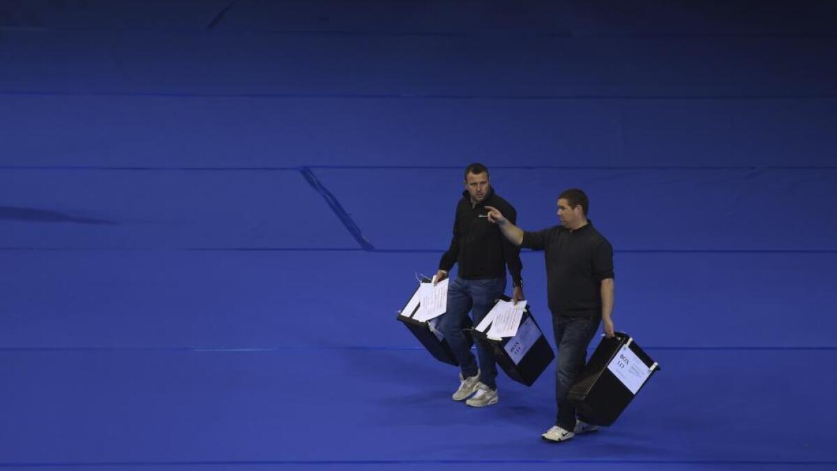 Workers begin carry ballots after polling stations closed in Glasgow, Scotland.