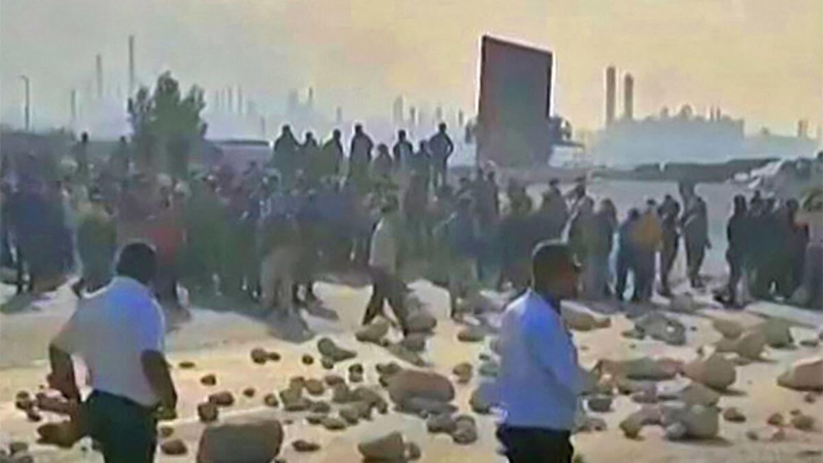 This image grab from a UGC video made available on twitter on October 10, 2022 reportedly shows employees blocking a road leading to the Asaluyeh Petrochemical Refinery in Iran's southwestern Bushehr province. — AFP file