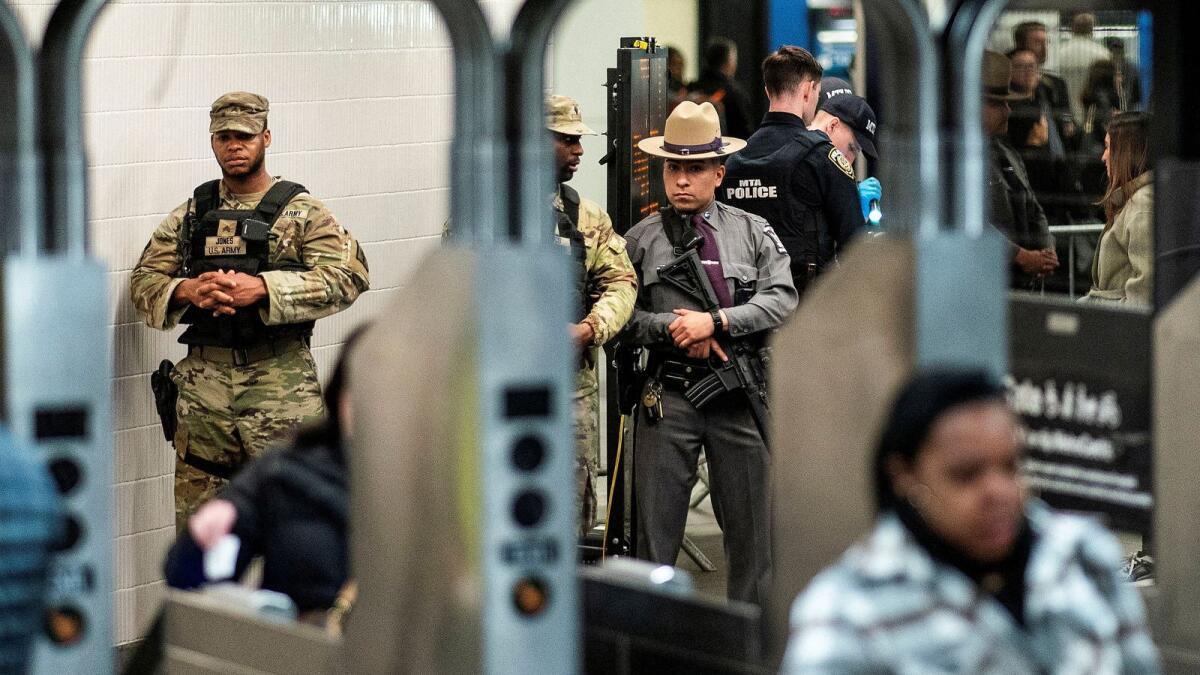 New York State Police officer and members of the New York State National Guard stand guard in a checkpoint to check bags inside the entrance of a subway station in New York City on March 7. Photo: Reuters