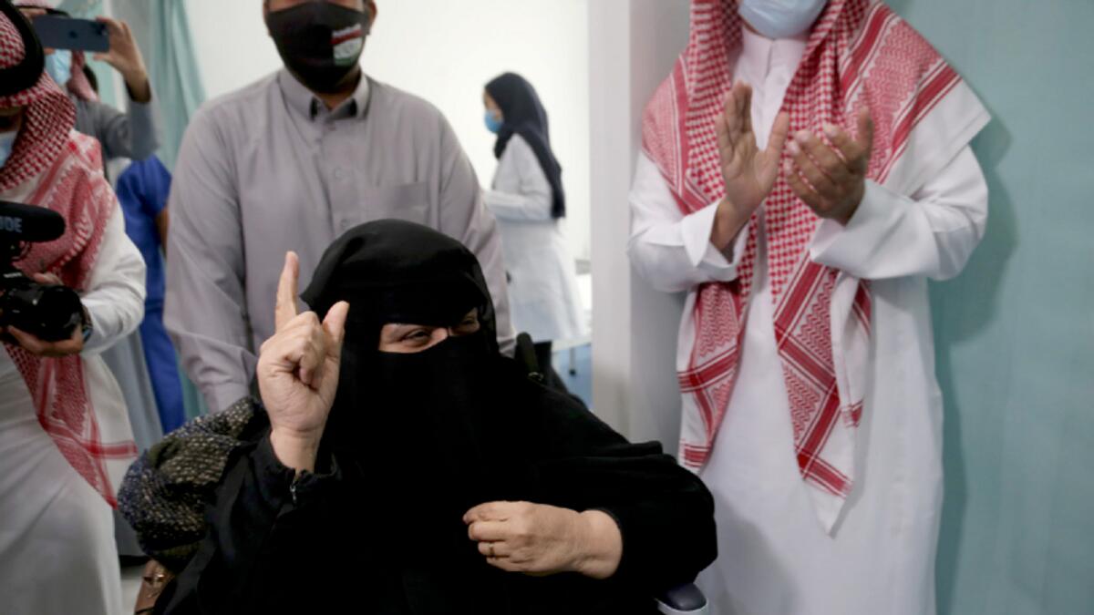 A Saudi woman gestures after she receiving the coronavirus vaccine.