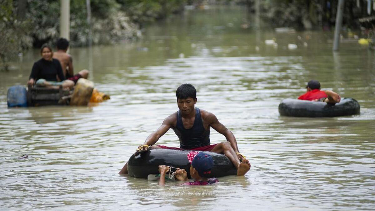 Flood-affected residents commute through floodwaters in Kalay, upper Myanmar's Sagaing region on August 3, 2015.