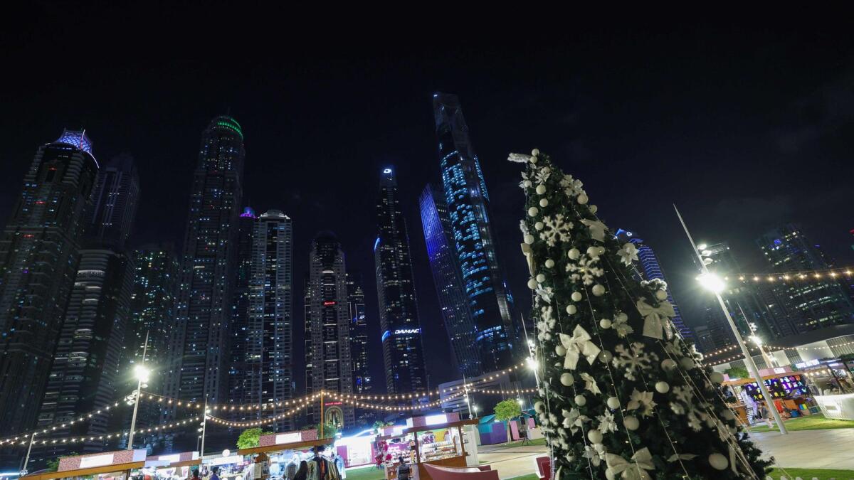 People take a stroll near a Christmas tree beneath the Dubai skyline. Supporting this optimism was a softening of price pressures, as purchasing costs rose to the least degree in almost a year. — AFP