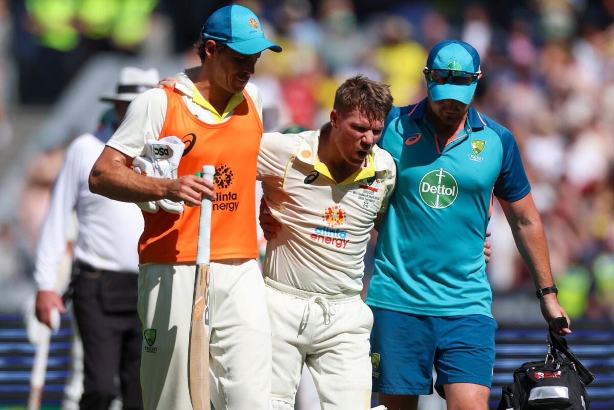 Australia's David Warner (centre) is helped by his teammates as he retires injured after reaching 200 runs during the second Test against South Africa. -- AP