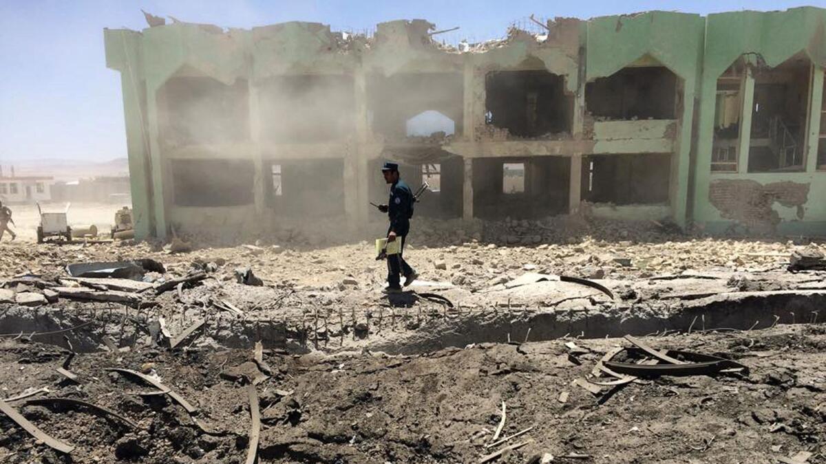 FILE. An Afghan policeman inspects the site of a suicide attack in Zabul on May 25, 2015. Photo: AFP