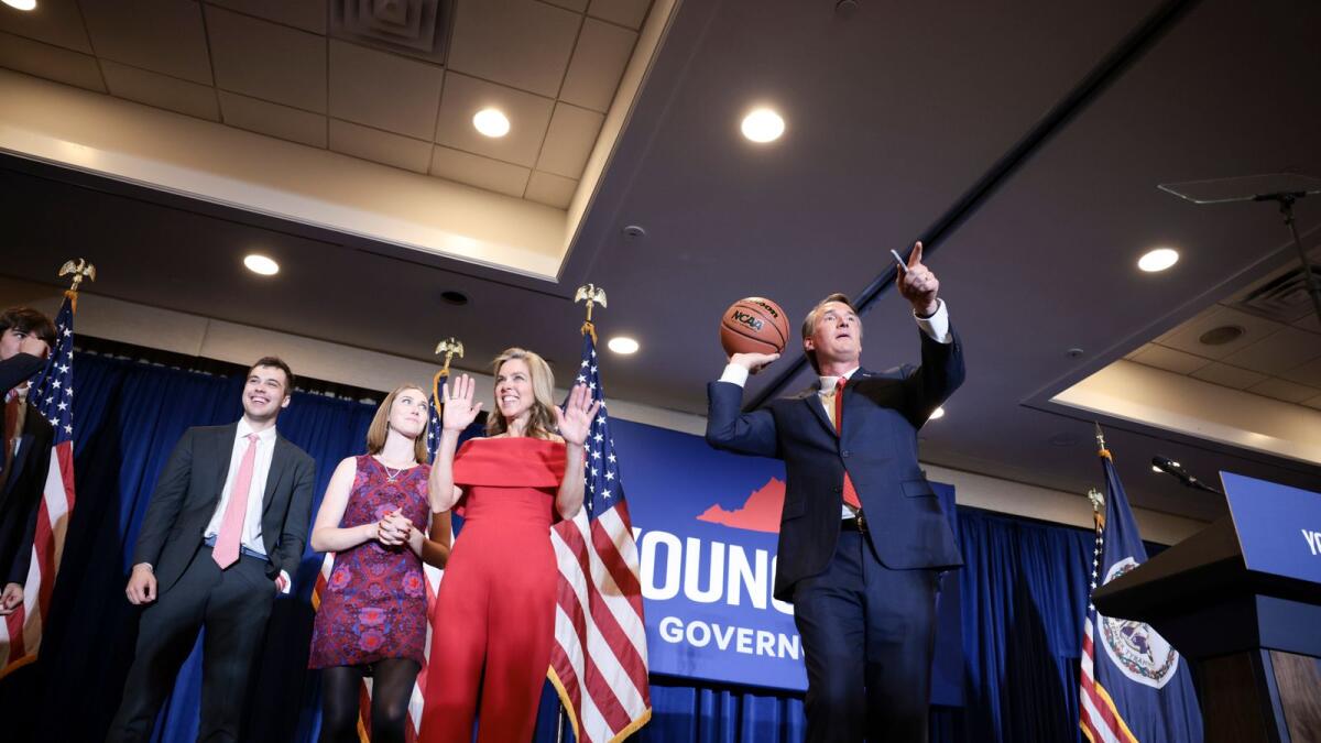 Virginia Republican gubernatorial candidate Glenn Youngkin passes an autographed basketball into the crowd with his family at his election night in Chantilly, Virginia. – AFP