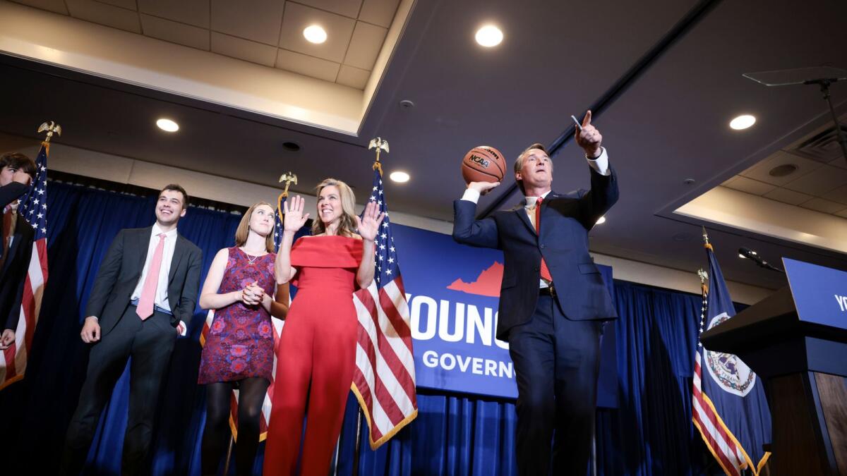 Virginia Republican gubernatorial candidate Glenn Youngkin passes an autographed basketball into the crowd with his family at his election night in Chantilly, Virginia. – AFP