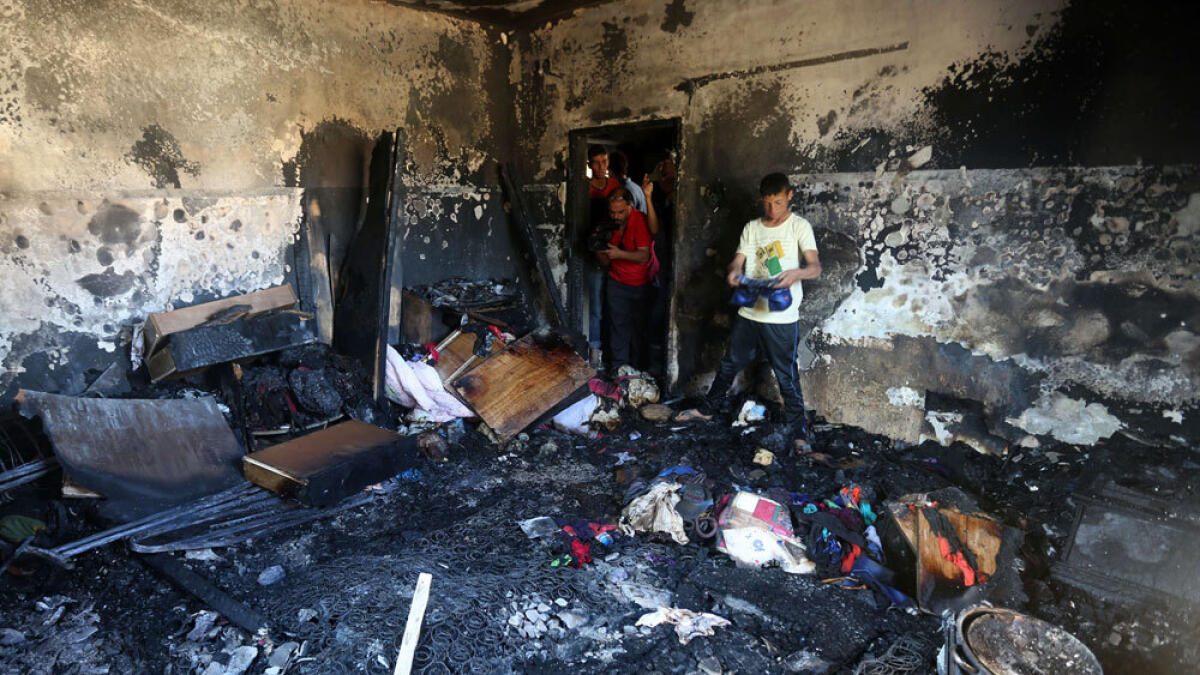 Palestinians look at the damage after a house was set on fire by Jewish settlers in the West Bank village of Duma.