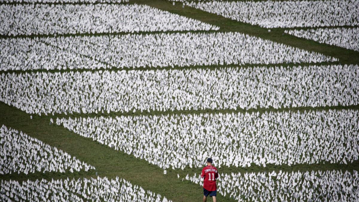 A man walks through the flags of the 'In America: Remember' public art installation near the Washington Monument on September 19. The installation commemorates all the Americans who have died due to Covid-19. — AFP