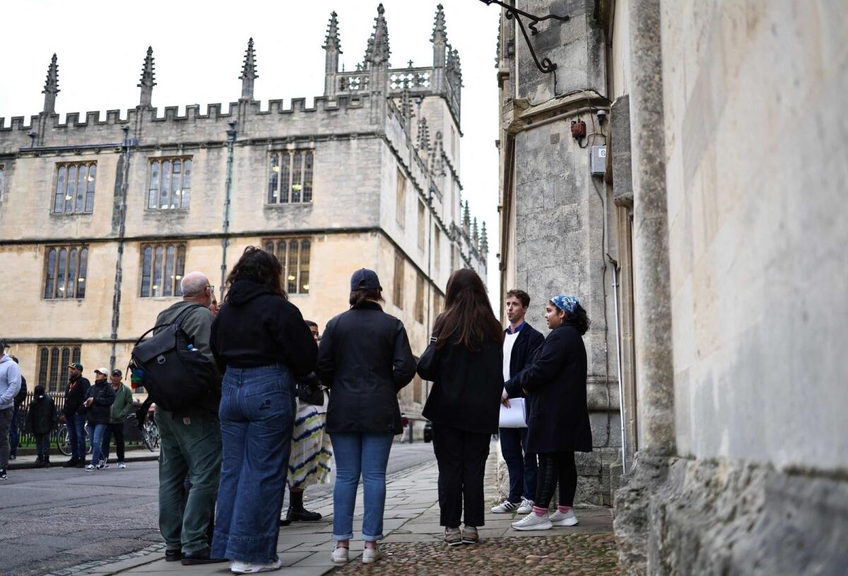 Tour guides Devika and Oliver talk with a group of people attending an 'Uncomfortable Oxford' tour outside the College of All Souls, in Oxford, on October 20, 2023. — AFP
