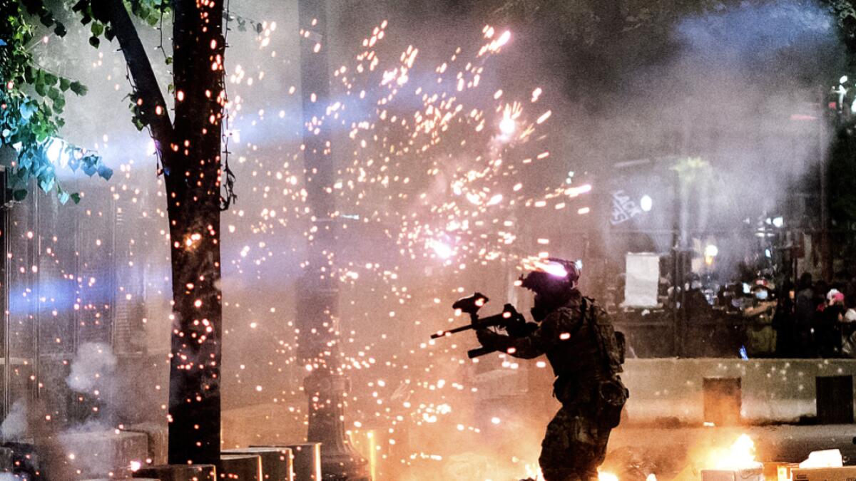 A federal officer fires crowd control munitions at Black Lives Matter protesters at the Mark O. Hatfield United States Courthouse, in Portland, Ore. Since federal officers arrived in downtown Portland in early July, violent protests have largely been limited to a two block radius from the courthouse. Photo: AP