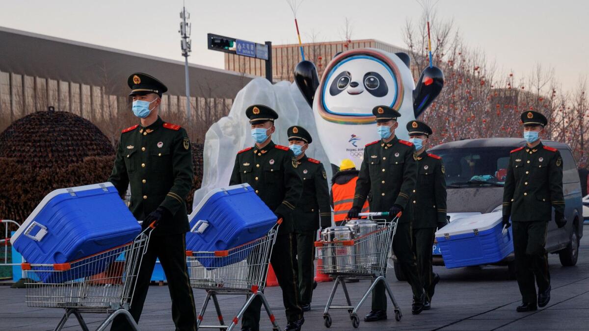 Paramilitary police officers walk past the mascot of the Beijing 2022 Winter Olympics in Beijing, China. (Reuters)
