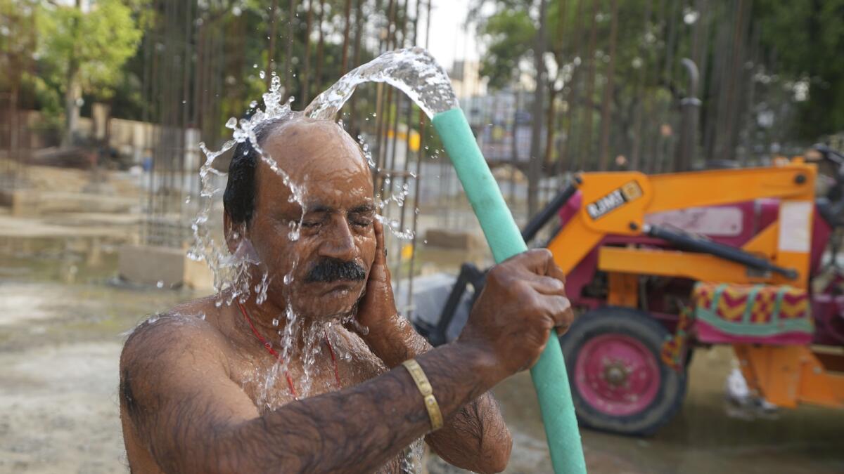 An Indian worker bathes at a building construction site as he tries to cool off on a hot day in Prayagraj. — AP