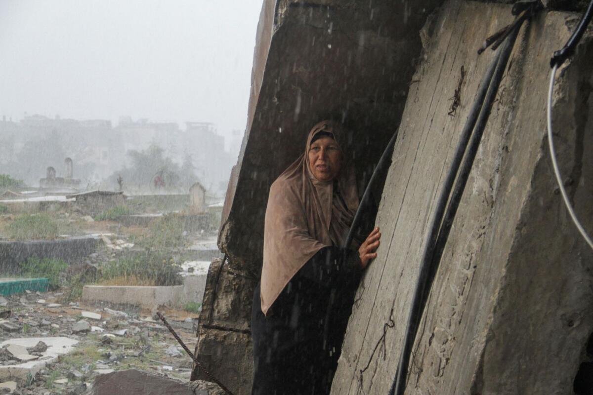 A woman shelters from the rain as Palestinians visit the graves of people who were killed in the ongoing conflict between Israel and Palestinian Islamist group Hamas, on the day of Eid Al Fitr, in Gaza Strip, on Wednesday.  Photo: Reuters