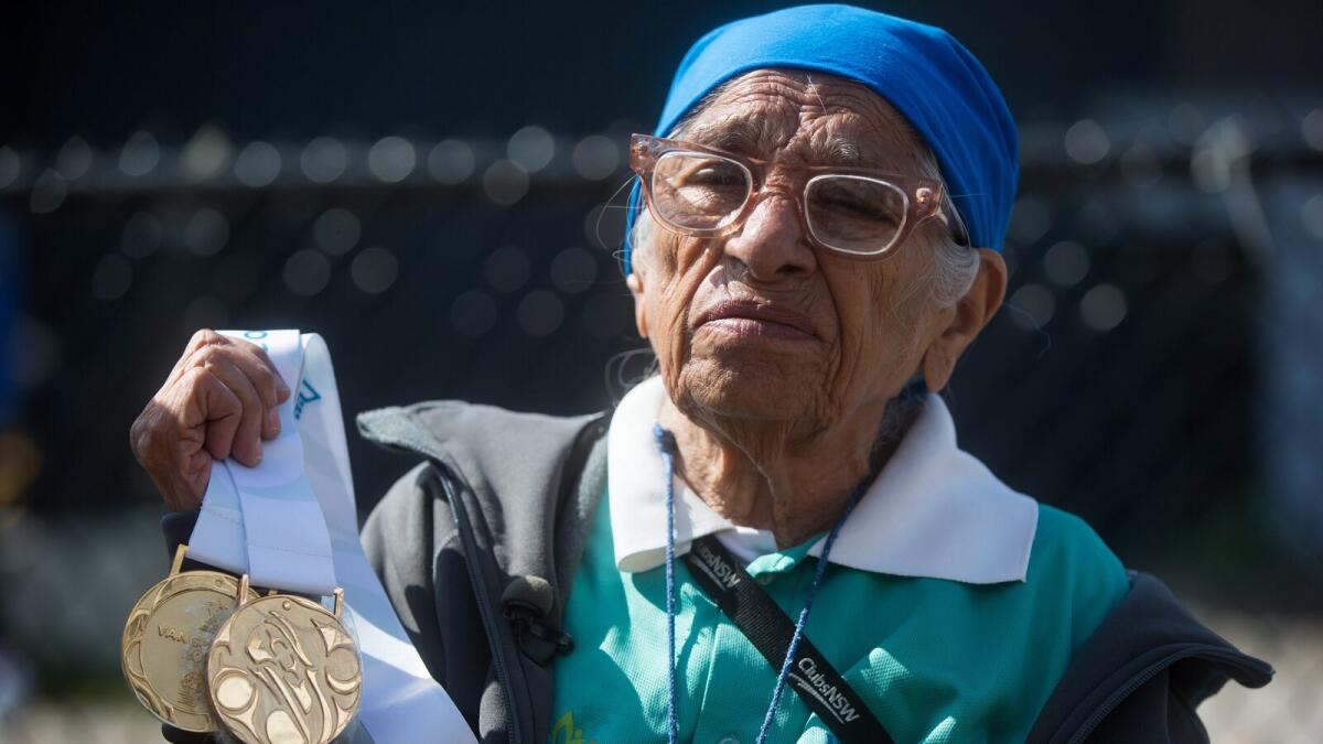 Man Kaur, 100, of India, holds the gold medals she won in shot put and javelin events before competing in the 100-meter track and field event at the Americas Masters Games in Vancouver, British Columbia, Monday, Aug. 29, 2016. More than 10,000 athletes aged 30 and older are participating in the games which continue until Sept. 4. (Darryl Dyck/The Canadian Press via AP)
