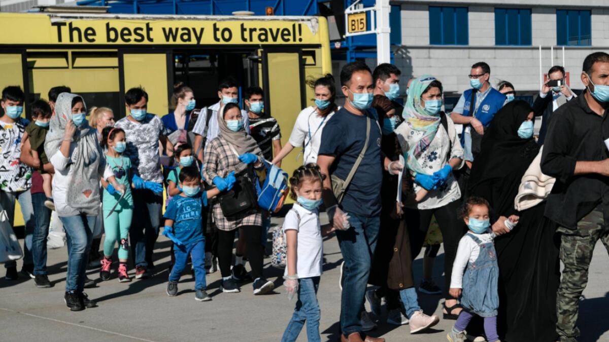 A group of 85 vulnerable refugees, mainly families with children with health problems, disembark a bus before boarding a plane for Germany as part of the EU relocation program from Greek islands' hotspots at Athens' international airport in Spata. Photo: AFP