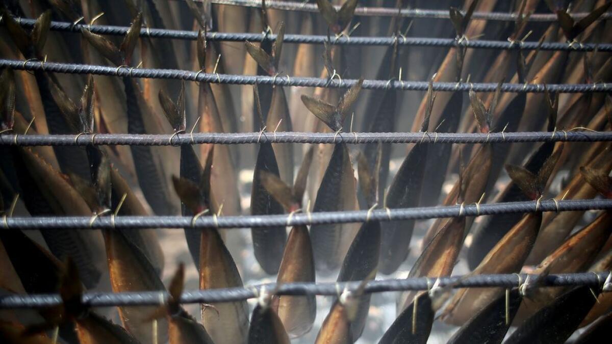 Mackerels are being smoked by Palestinians before selling them at a market ahead of the Eid al-Fitr