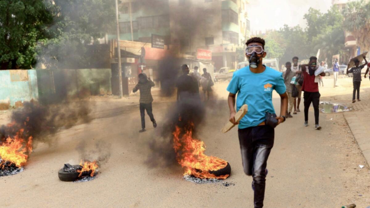 Protesters march past burning tires during a rally against the military rule. — Reuters file