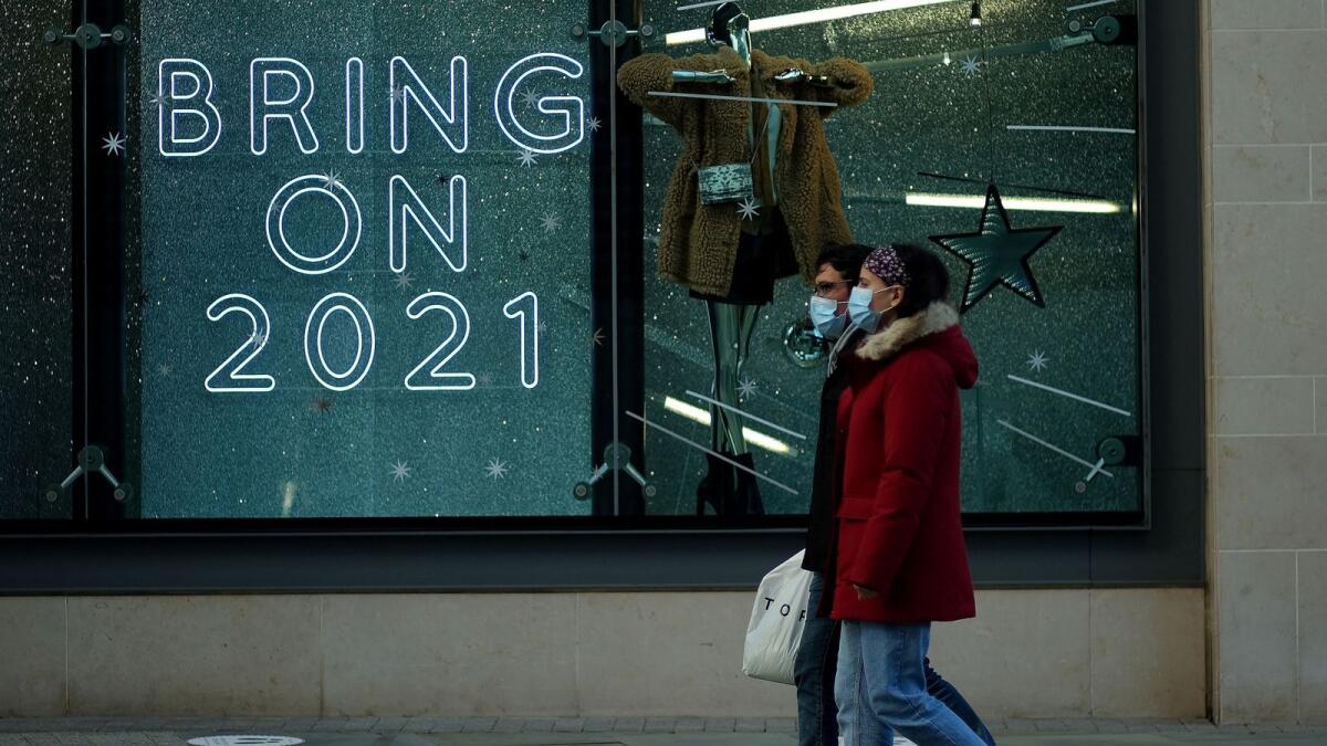 People walk past a sign in a shop window amid the outbreak of the coronavirus disease (COVID-19) in Manchester, Britain, December 15, 2020.