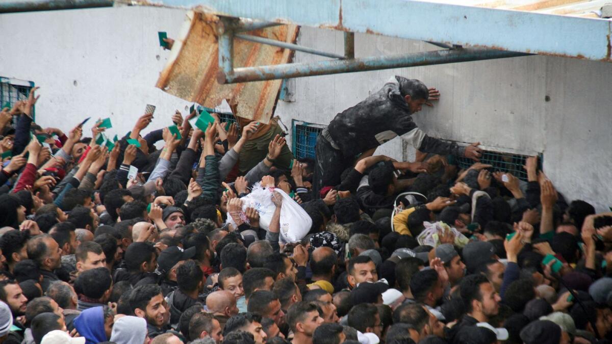 Palestinians gather to receive aid outside an UNRWA warehouse as Gaza residents face crisis levels of hunger. — Reuters