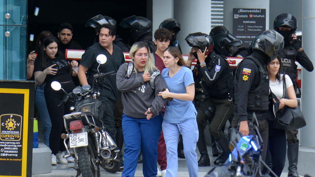 People are helped out of the premises of Ecuador's TC television channel after unidentified gunmen burst into the state-owned television studio live on air on January 9, 2024, in Guayaquil, Ecuador. — AFP